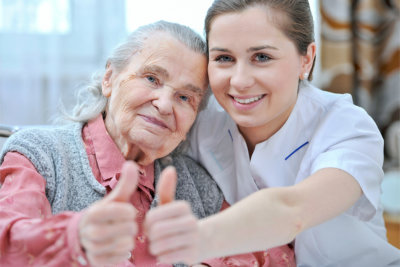 nurse and senior woman giving thumbs up